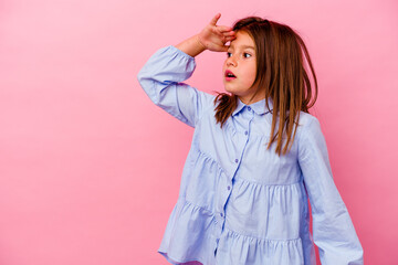 Little caucasian girl isolated on pink background  looking far away keeping hand on forehead.