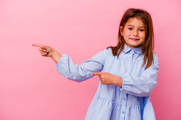 Little caucasian girl isolated on pink background  excited pointing with forefingers away.