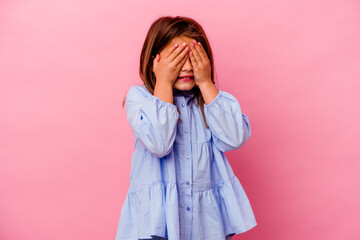 Little caucasian girl isolated on pink background  covers eyes with hands, smiles broadly waiting for a surprise.