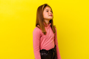 Little caucasian girl isolated on yellow background relaxed and happy laughing, neck stretched...