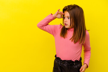 Little caucasian girl isolated on yellow background looking far away keeping hand on forehead.