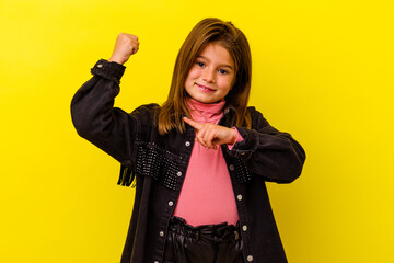 Little caucasian girl isolated on yellow background showing strength gesture with arms, symbol of...