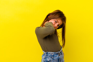 Little caucasian girl isolated on yellow background having a neck pain due to stress, massaging and...