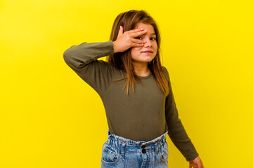 Little caucasian girl isolated on yellow background covers eyes with hands, smiles broadly waiting...