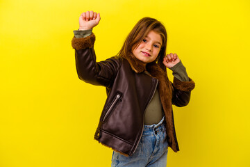 Little caucasian girl isolated on yellow background dancing and having fun.