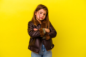 Little caucasian girl isolated on yellow background suspicious, uncertain, examining you.