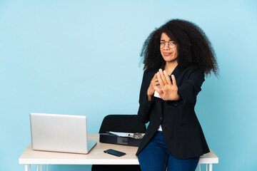 African american business woman working in her workplace nervous stretching hands to the front