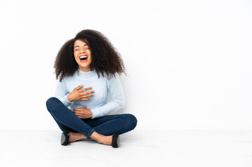 Young african american woman sitting on the floor smiling a lot