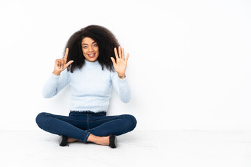 Young african american woman sitting on the floor counting seven with fingers