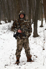 The man with machine gun in the snowy forest