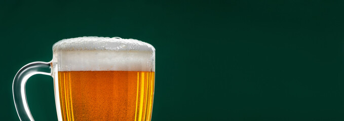 Mug with traditional Irish pale ale on a dark green background. Bubbles in a glass of beer.