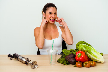 Young caucasian woman preparing a healthy smoothie with vegetables