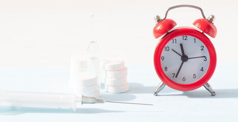Pills, syringe and red alarm clock on white background. Medical and health concept in minimal style. Medicine in hospital. Retail drug market.