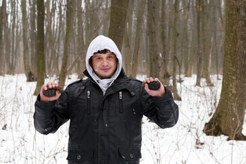 A man with grenade in his hands in the snowy forest