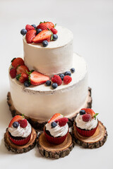 red cream cupcakes with strawberries and blueberries on natural wood coasters