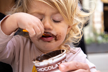 Baby girl eating chocolate icecream