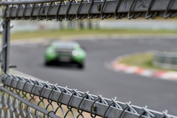 Steel safety fence around the race track and a race car in background