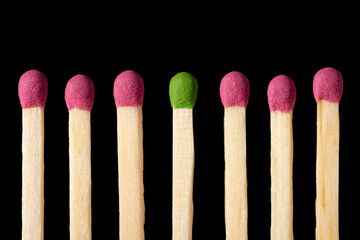 Green match in the middle of red matches. Different, stand out from the crowd symbol