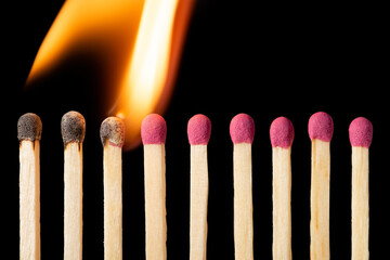 Line of matches igniting one by one. Burning matches on the black background
