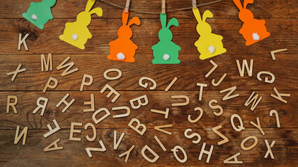 Easter background. Garland of paper rabbits and letters on wooden background