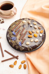 Homemade chocolate brownie cake with caramel cream and almonds with cup of coffee on a white concrete  background. Side view.