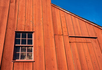 Red wood frame barn siding against a blue sky