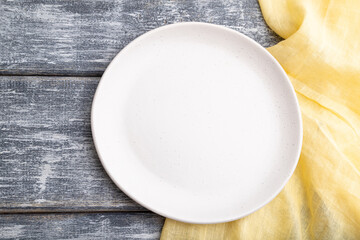 Empty white ceramic plate on gray wooden background. Top view, close up.