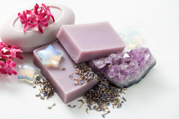 Obraz na płótnie Canvas Handmade natural soap, dried lavender flowers, amethyst crystal, pink flowers on a white background. Items for spa care and water treatments