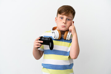 Little redhead boy holding a game pad isolated on white background thinking an idea