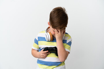 Little redhead boy holding a game pad isolated on white background with tired and sick expression