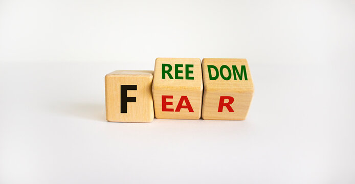 Freedom from fear symbol. Turned wooden cubes and changed the word 'fear' to 'freedom'. Beautiful white background, copy space. Business, motivational and freedom from fear concept.