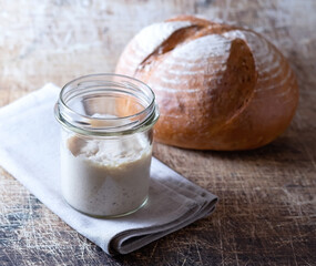 Sourdough in a jar and bread on an old table.