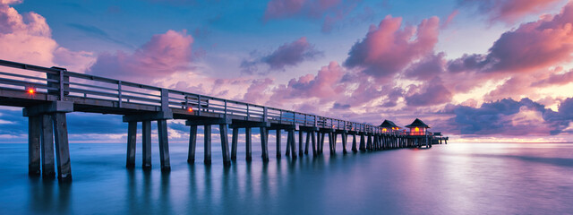 A scenic colorful sunset at the beach with a breathtaking boardwalk