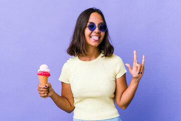 Young mixed race woman eating an ice cream showing a horns gesture as a revolution concept.