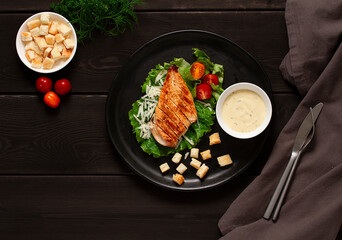 Caesar salad with chiken , on a black  wooden table, top view, no people,