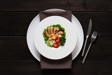 Caesar salad with chiken , on a black  wooden table, top view, no people,
