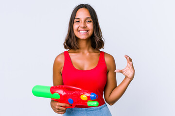 Young mixed race woman holding a water gun isolated holding something with palms, offering to camera.