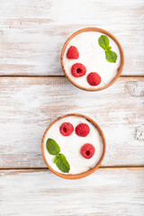 Yogurt with raspberry in clay cups on white wooden background. top view.