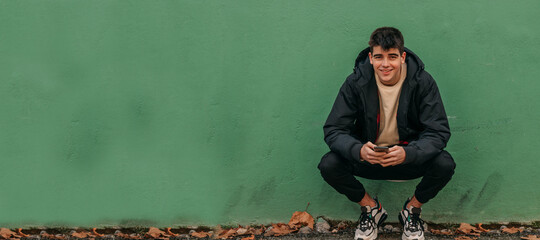 young man on the street wall with mobile phone