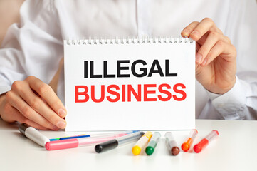 A sheet of paper with text ILLEGAL BUSINESS, multicolored markers on a white table. Business and...