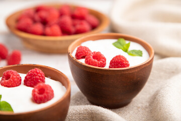 Yogurt with raspberry in clay cups on white wooden background. Side view, selective focus.