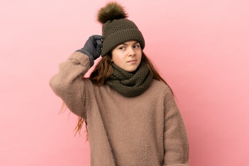 Little girl with winter hat isolated on pink background having doubts