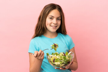 Little caucasian girl isolated on pink background holding a bowl of salad with happy expression