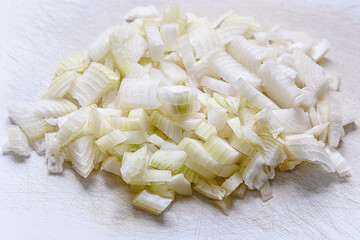 chopped onions on a white cutting board close up