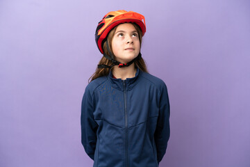 Little caucasian girl isolated on purple background and looking up