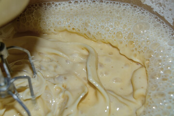 Household mixer whips milk mixture in kitchen utensils close-up