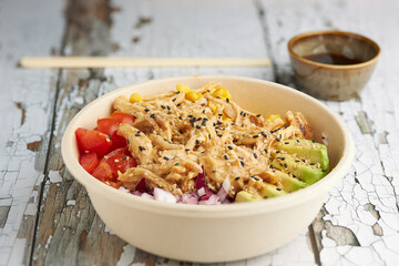 Close-up of an avocado chicken poke and cherry tomatoes.