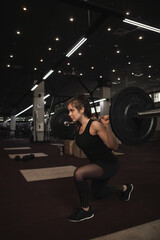 Fototapeta na wymiar Vertical shot of a sportwoman doing lunges with barbell