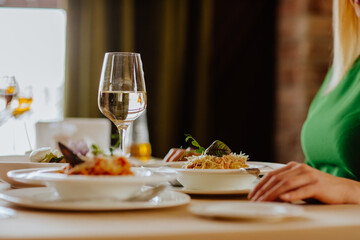 Serving of carbonara pasta and glass of white wine in restaurant.