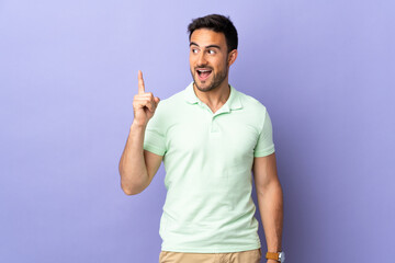 Young handsome man isolated on purple background intending to realizes the solution while lifting a finger up